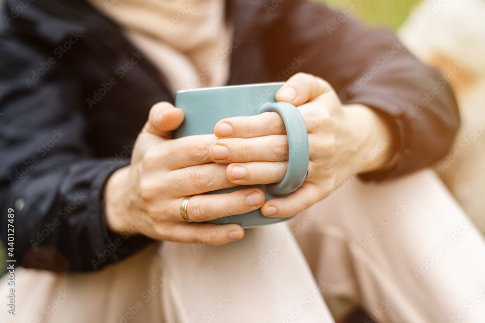Woman with a cup in the forest, park in cool weather on a green background of foliage. Relaxation in nature, rest. Woman with a cup in the forest, park in cool weather on a green background of foliage. Relaxation in nature, rest.
