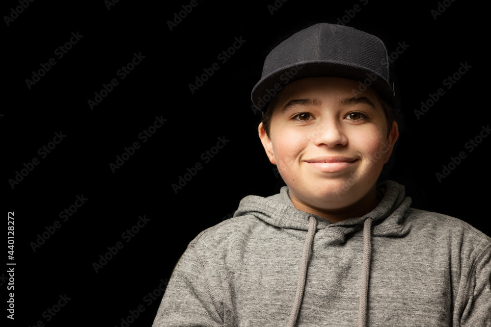 Smiling boy wearing cap in front of black background Smiling boy wearing cap in front of black background