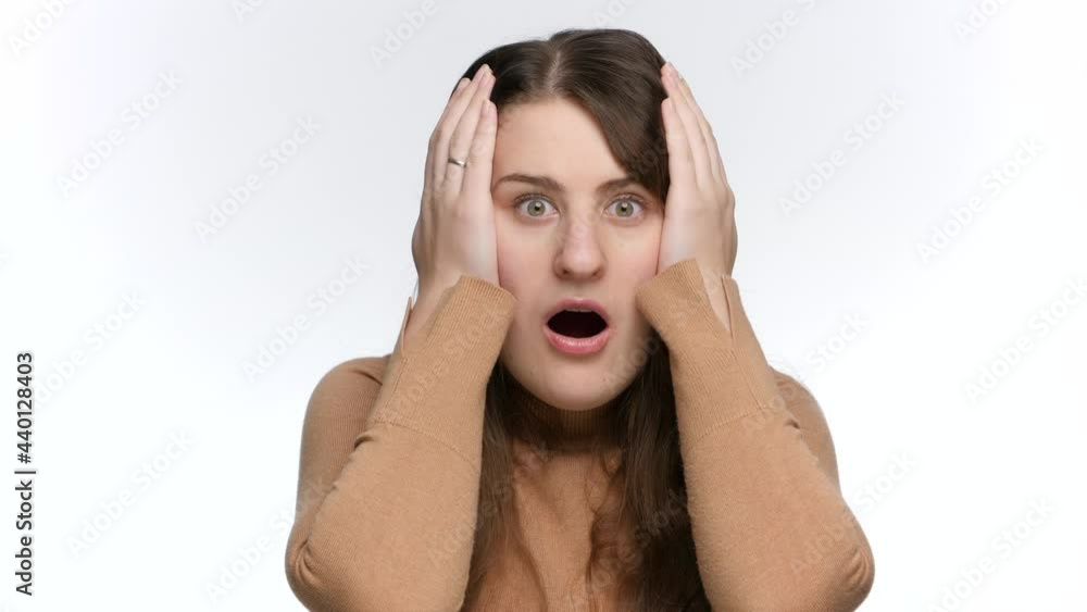 Shocked and stressed woman opens her mouth and holds head with hands. Shock and negative emotions Shocked and stressed woman opens her mouth and holds head with hands. Shock and negative emotions