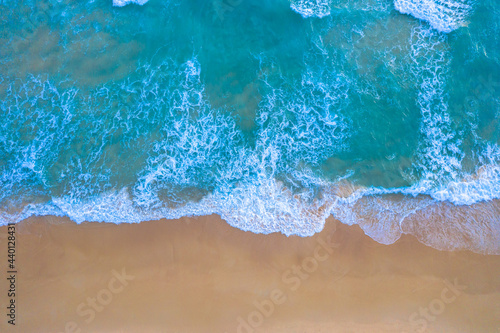 aerial top view Wave after wave swept towards the shore. . white foamy waves crash along the beach..Beach sea space area. Blue sea, waves crashing at Karon Beach, Phuket.