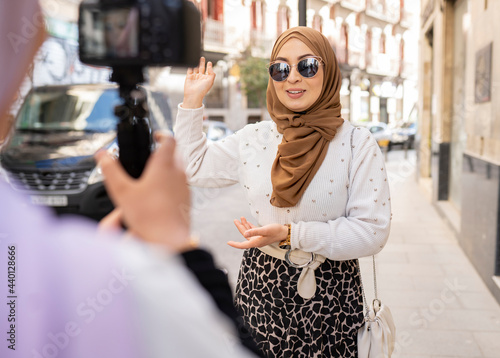 Young woman with sunglasses gesturing while vlogging in city photo