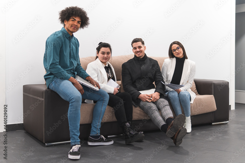 Multi-ethnic male and female entrepreneurs sitting on sofa at office Multi-ethnic male and female entrepreneurs sitting on sofa at office