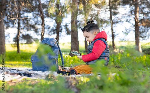 Boy holding magnifying glass while sitting in public park photo