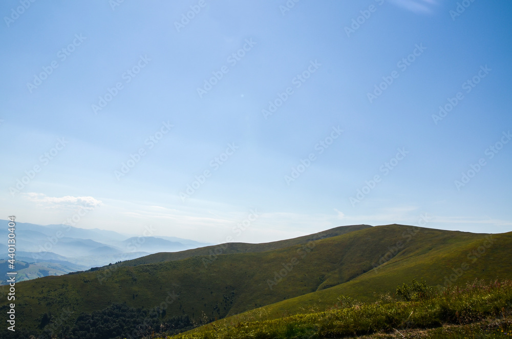 Beautiful scenic view of rolling grassy field and mountain ridge of Borzhava meadow in sunny summer day. Carpathian mountains, Ukraine Beautiful scenic view of rolling grassy field and mountain ridge of Borzhava meadow in sunny summer day. Carpathian mountains, Ukraine