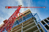 Highrise Building Site in Berlin. Looking up at the construction site of a high-rise building with red crane in the foreground.