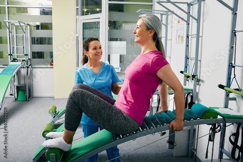 Woman recovering from a lumbar spine injury in a rehabilitation center while sitting on special recovery table with her physiotherapist photo