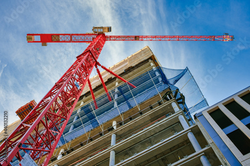 Highrise Building Site in Berlin. Looking up at the construction site of a high-rise building with red crane in the foreground. photo