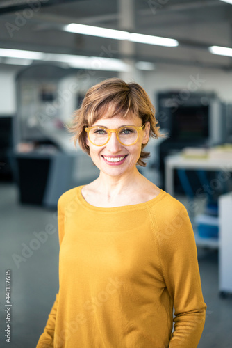 Female mature owner wearing eyeglasses standing in factory photo