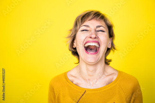 Woman laughing in front of yellow background photo