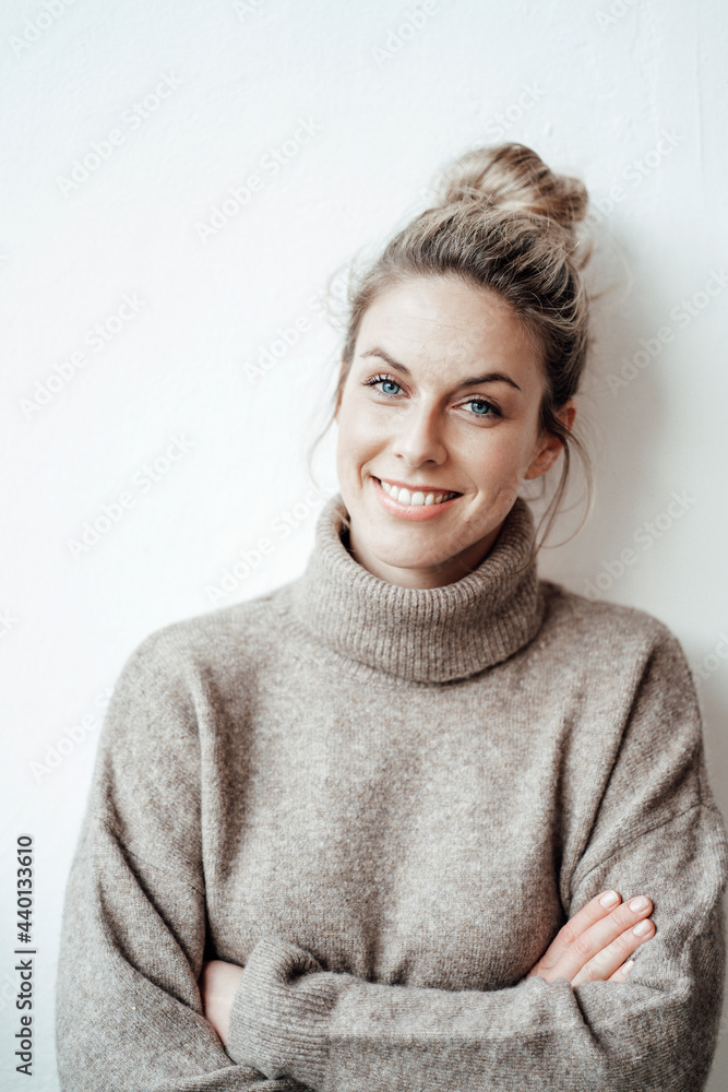 Smiling mid adult woman with arms crossed leaning on white wall Smiling mid adult woman with arms crossed leaning on white wall