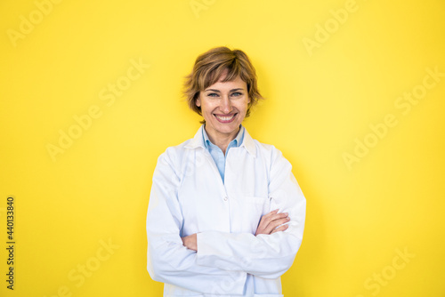 Smiling female scientist standing with arms crossed in front of wall photo