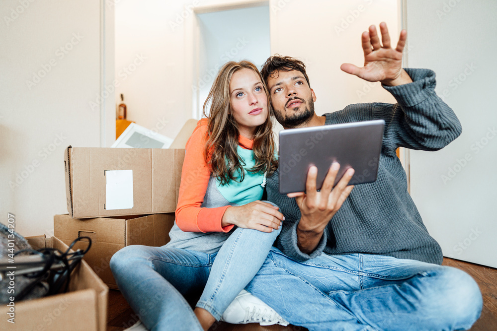 Young couple sitting with digital tablet planning at home Young couple sitting with digital tablet planning at home