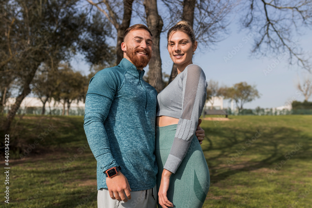 Smiling young couple standing in public park Smiling young couple standing in public park