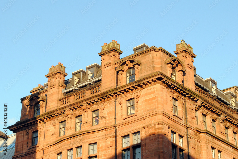 Roofline of Victorian Stone Office Building seen in  Warm Evening Light against Blue Sky 