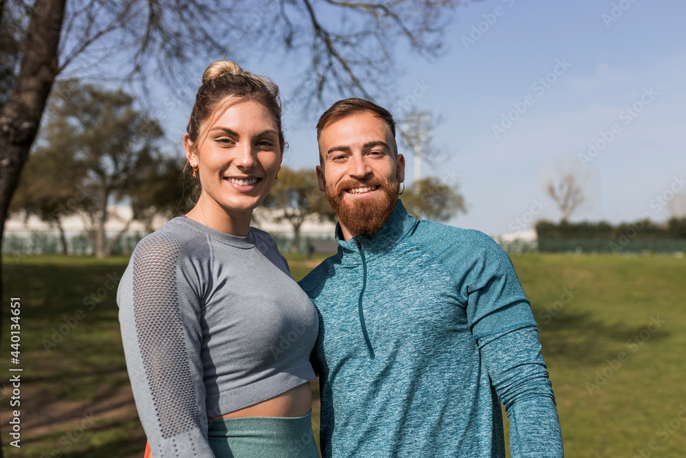 Smiling young couple standing in public park during sunny day Smiling young couple standing in public park during sunny day