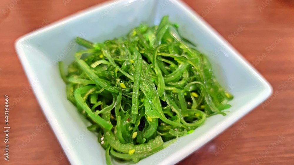 Chuka seaweed salad (Hiyashi Wakame), Seasoned seaweed in white square plate on wooden table. Japanese food.