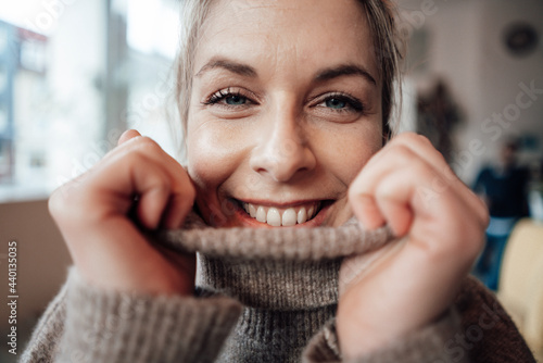 Woman with turtleneck sweater smiling at cafe