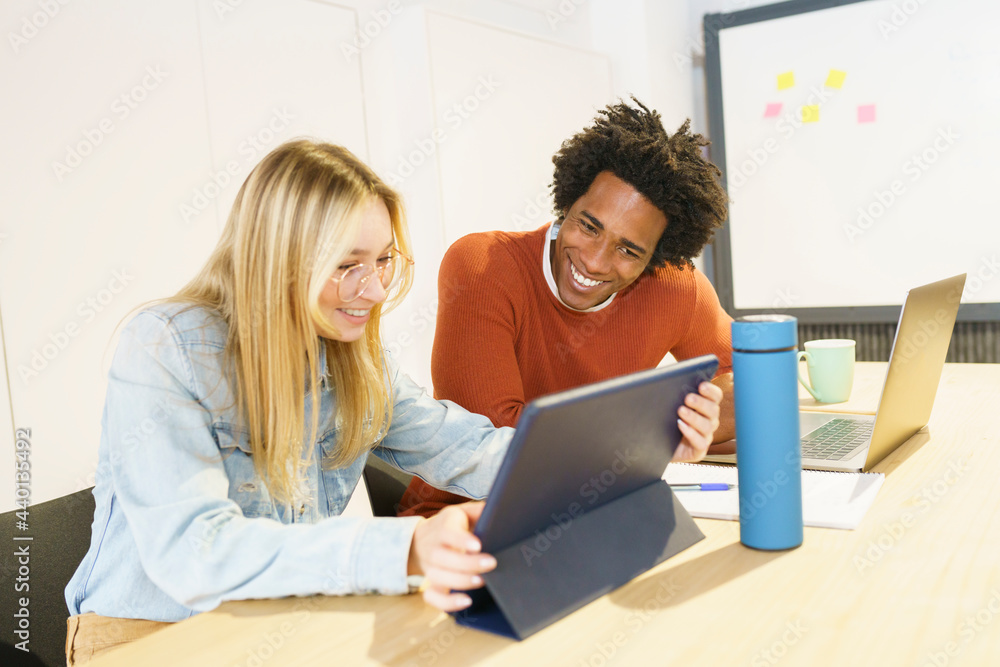 Smiling multi-ethnic male and female professionals working on digital tablet in office Smiling multi-ethnic male and female professionals working on digital tablet in office