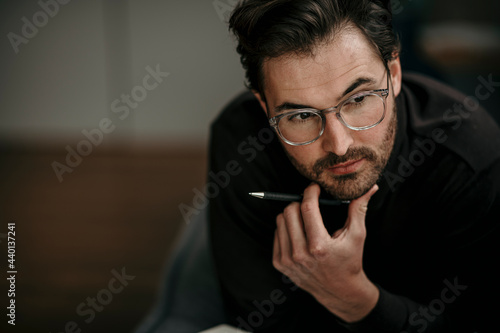 Serious businessman with hand on chin contemplating at home office