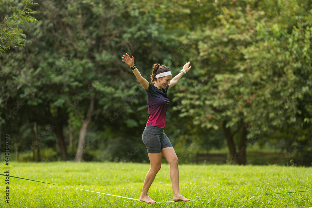 Female athlete slacklining at public park Female athlete slacklining at public park