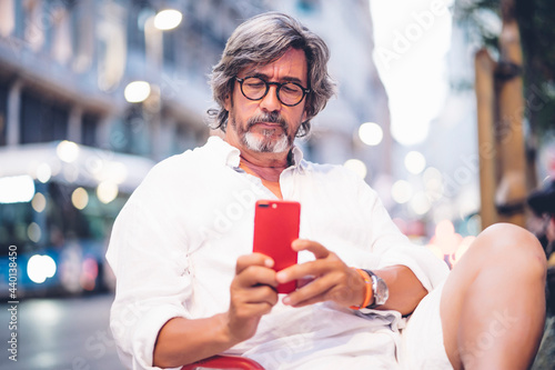 Attractive senior man using mobile phone while sitting at sidewalk cafe in Madrid photo