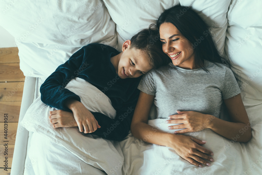 Smiling son and mother lying on bed at home Smiling son and mother lying on bed at home