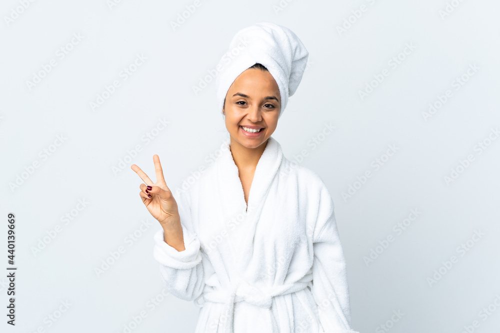Young woman in bathrobe over isolated white background smiling and showing victory sign Young woman in bathrobe over isolated white background smiling and showing victory sign