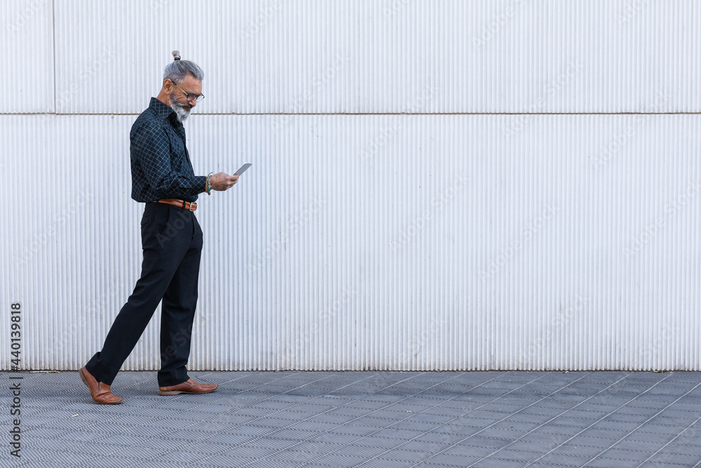 Male professional using smart phone while walking on footpath Male professional using smart phone while walking on footpath