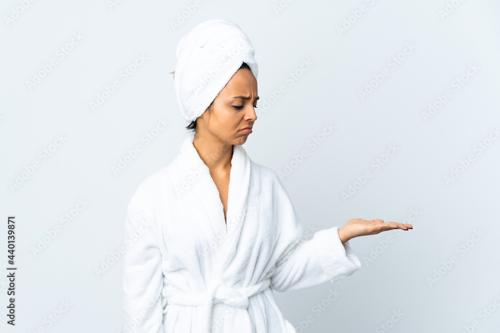 Young woman in bathrobe over isolated white background holding copyspace with doubts Young woman in bathrobe over isolated white background holding copyspace with doubts