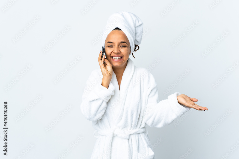 Young woman in bathrobe over isolated white background keeping a conversation with the mobile phone with someone Young woman in bathrobe over isolated white background keeping a conversation with the mobile phone with someone