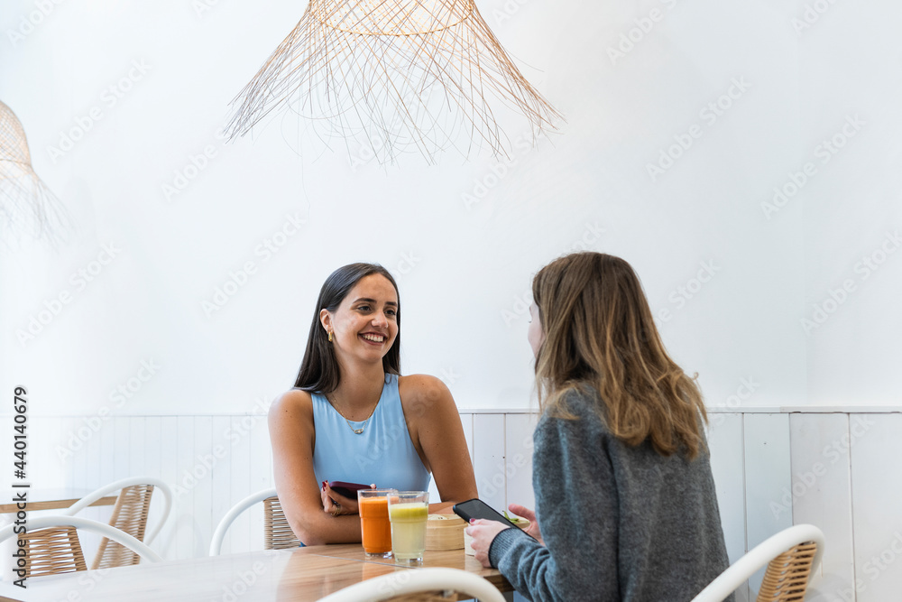 © NOVELLIMAGE/Westend61 - Female friends talking to each other while sitting at cafe