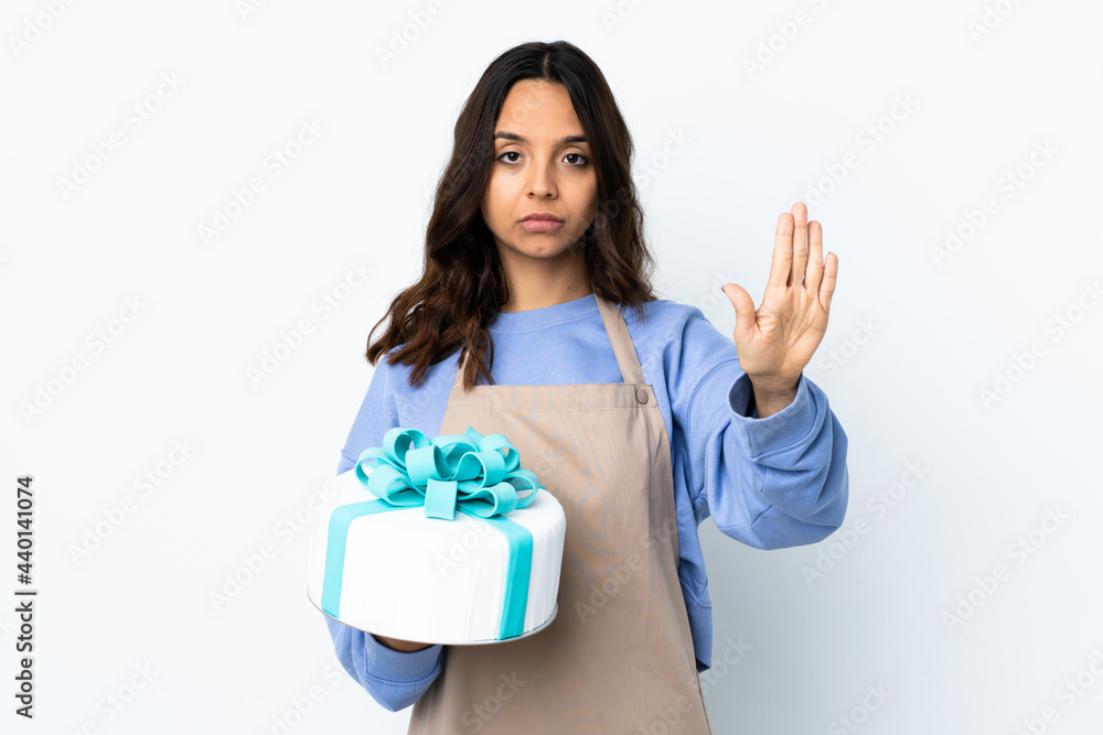Pastry chef holding a big cake over isolated white background making stop gesture Pastry chef holding a big cake over isolated white background making stop gesture