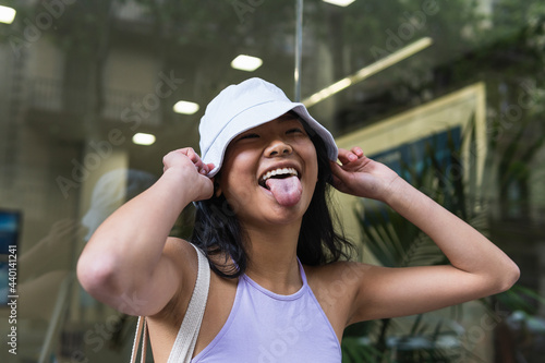 Woman sticking out tongue while holding bucket hat outdoors photo