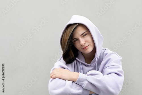 Beautiful girl in purple hooded shirt by gray wall photo
