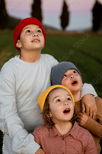 Brothers and sister wearing knit hat with mouth open looking up