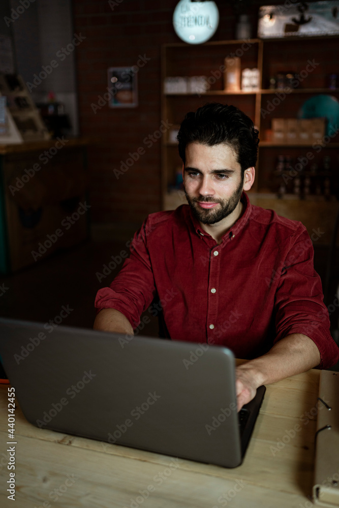 Male freelance worker working on laptop while sitting in coffee shop Male freelance worker working on laptop while sitting in coffee shop