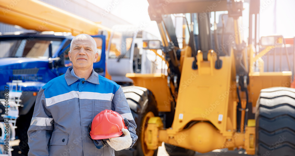 Excavator driver in hard hat stands at construction equipment, concept banner industrial man portrait Excavator driver in hard hat stands at construction equipment, concept banner industrial man portrait