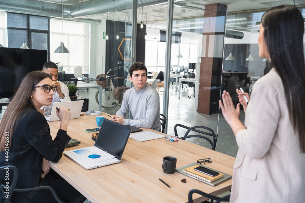 © SERGIO NIEVAS/Westend61 - Male and female professionals looking at businesswoman gesturing during meeting in office