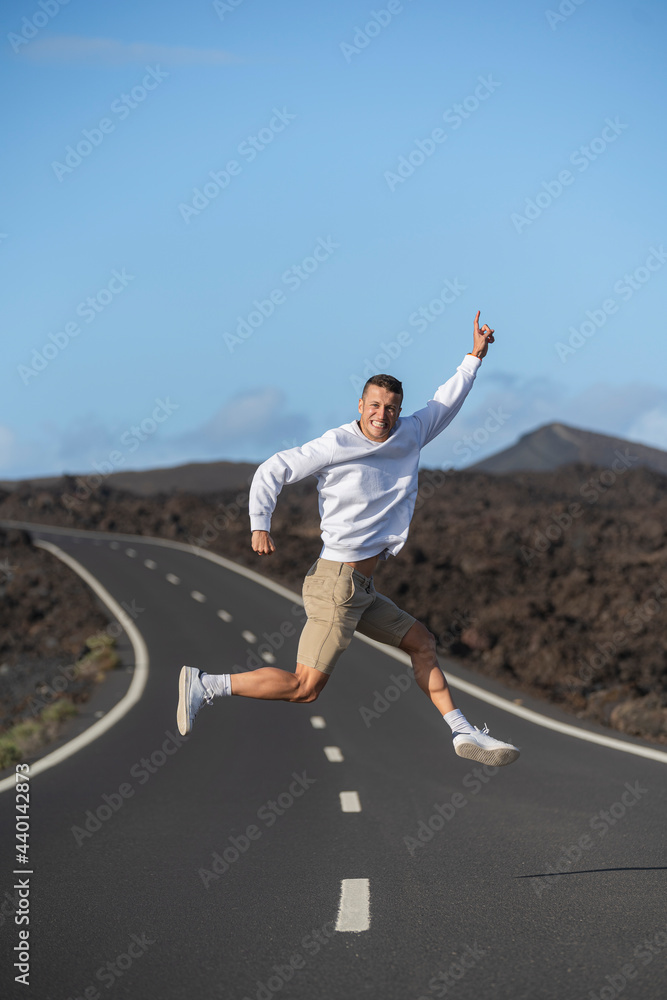 Smiling male tourist gesturing and jumping over road Smiling male tourist gesturing and jumping over road