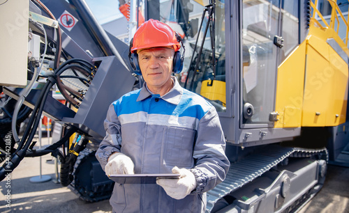 Industry operator use mobile tablet for control drilling rig for exploration of minerals for oil, gas and artisan water photo