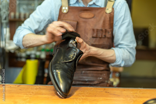 Male cobbler holding shoe while polishing at workshop photo