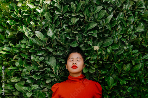 Woman with eyes closed in front of green plants photo