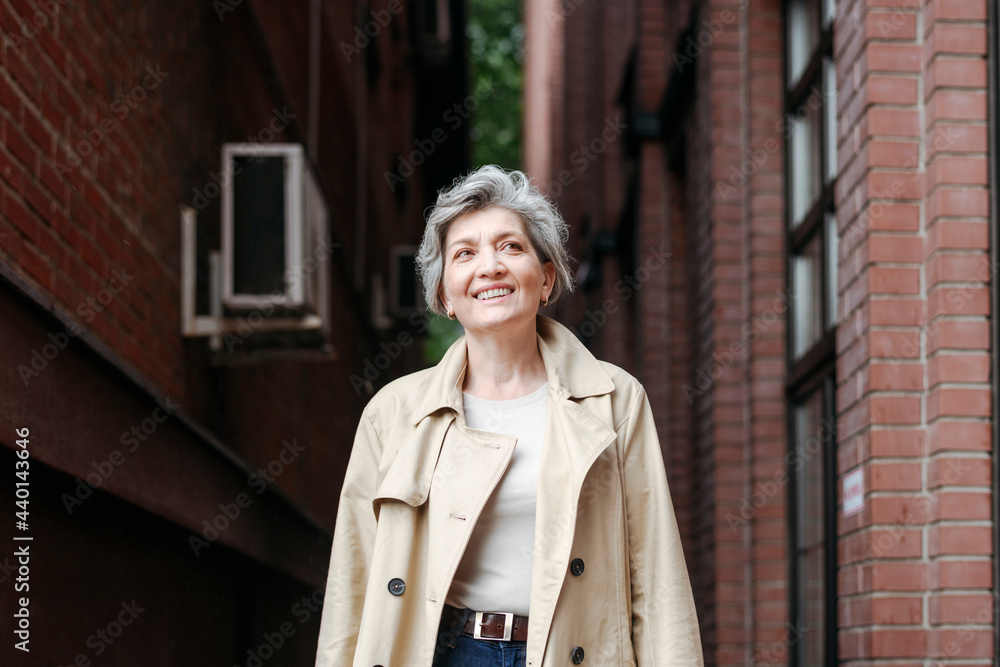 Smiling mature woman looking away while standing by building Smiling mature woman looking away while standing by building