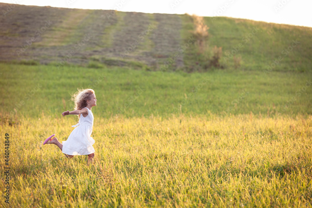 Girl with arms outstretched running in meadow during sunset Girl with arms outstretched running in meadow during sunset