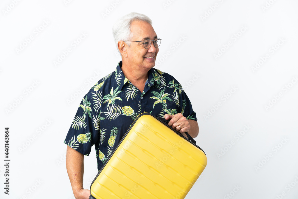 Middle age Brazilian man isolated on white background in vacation with travel suitcase Middle age Brazilian man isolated on white background in vacation with travel suitcase