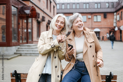 Cheerful female friends listening music while sharing headphones photo