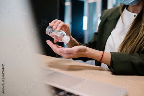 Woman using hand sanitizer at office photo