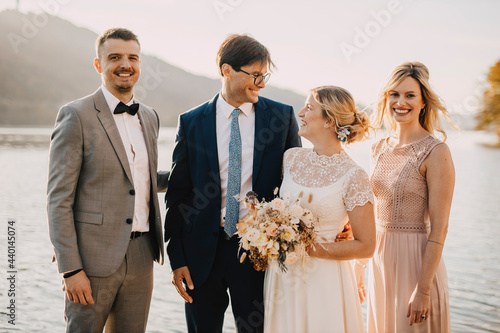 Smiling bride and groom with guests during wedding ceremony photo