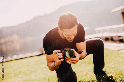 Young man crouching while using camera on lawn photo