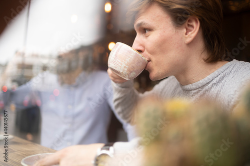 Handsome businessman having coffee in office seen through glass photo